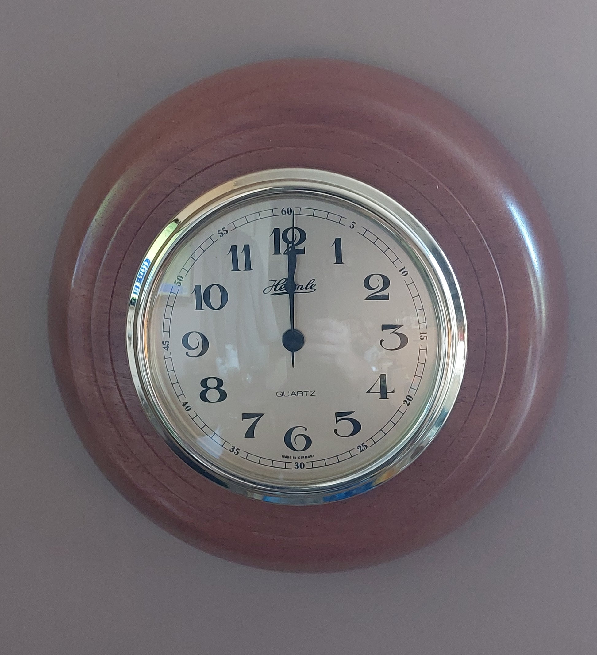 A round wall clock with a reddish-brown wood-grain outer frame, a silver metal bezel, and a white dial with black Arabic numerals. The brand name 'Kershaw' is visible on the clock face.