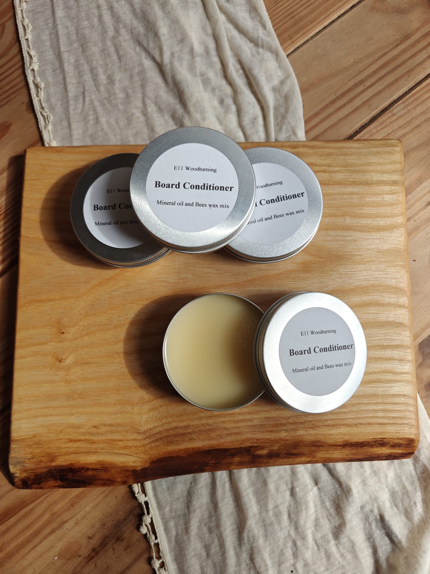 Tins of Serving Board Conditioner Butter.  Four tins on a serving board. 